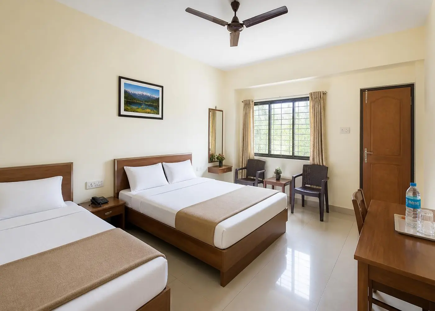 Neat budget non-AC room with two beds, ceiling fan and clean tiled floor